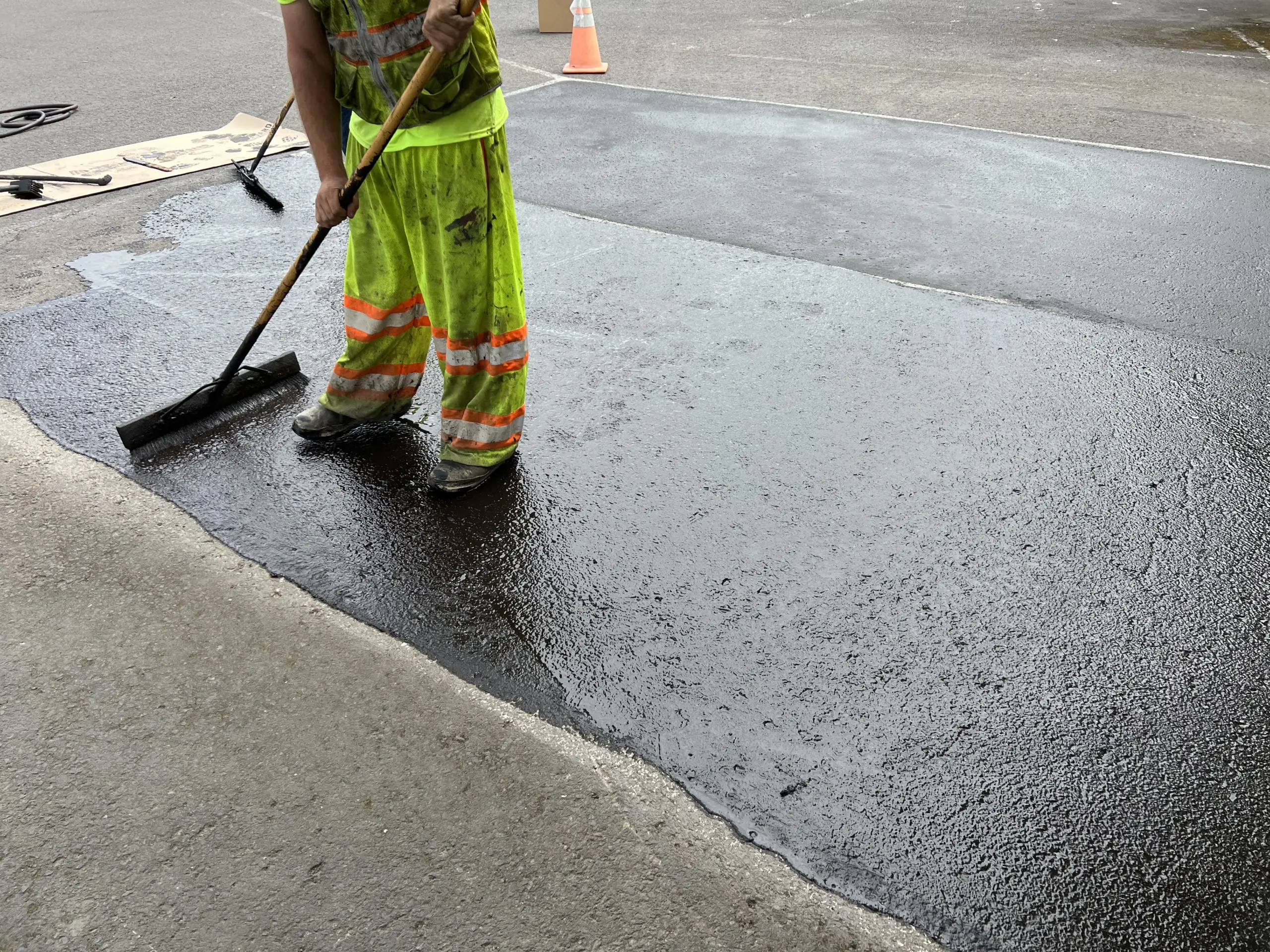 applying sealer pigment via broom on pavement for parkinglot