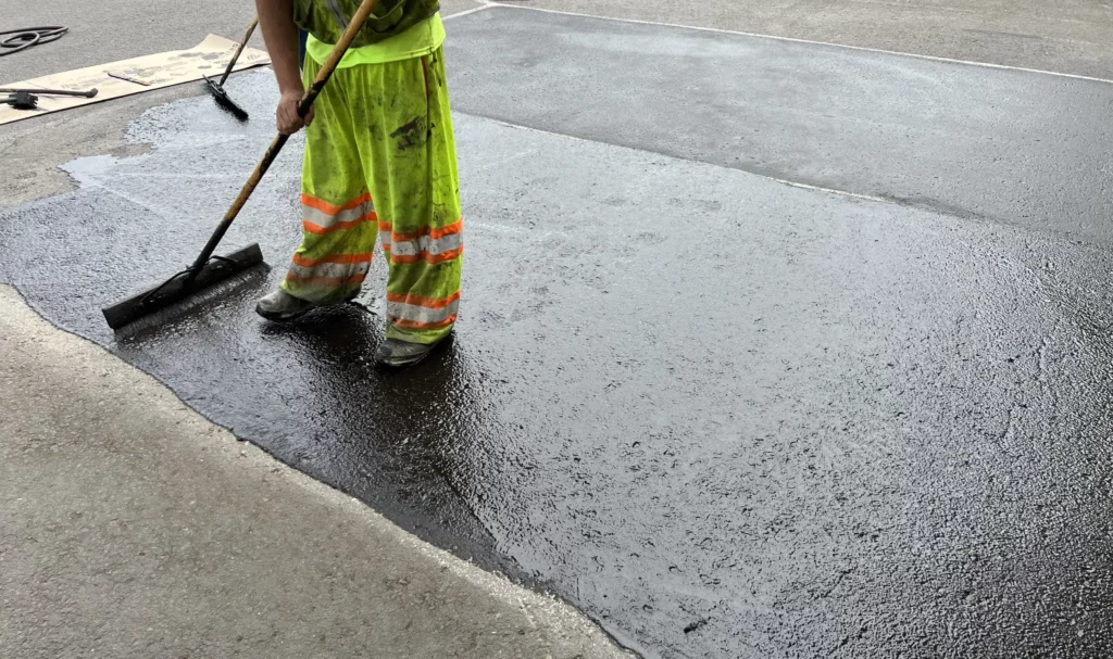 applying sealer pigment via broom on pavement for parkinglot