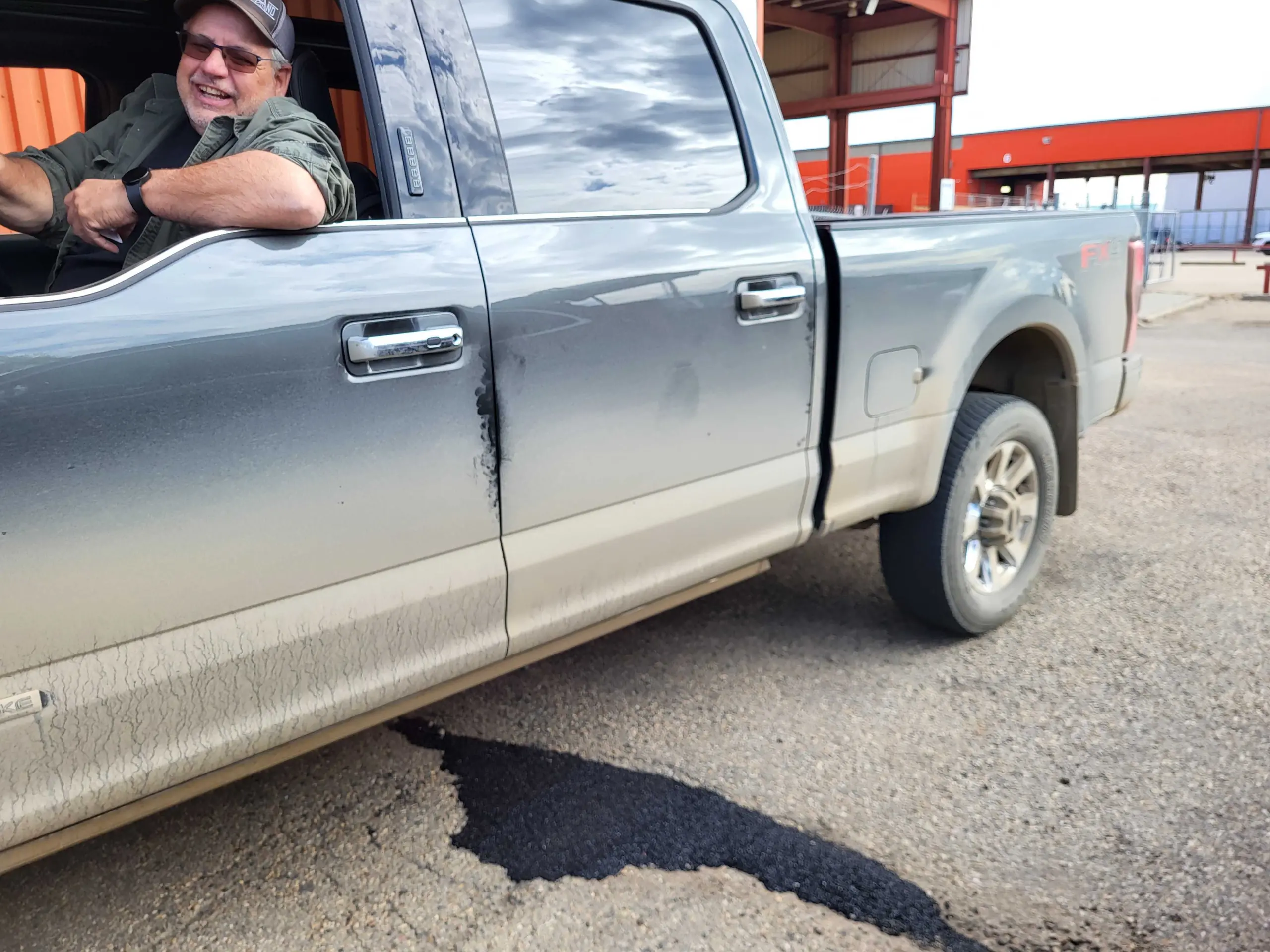 logistics and warehouse manager drives his Ford F-250 truck over a pothole filled with cold-patch from modern